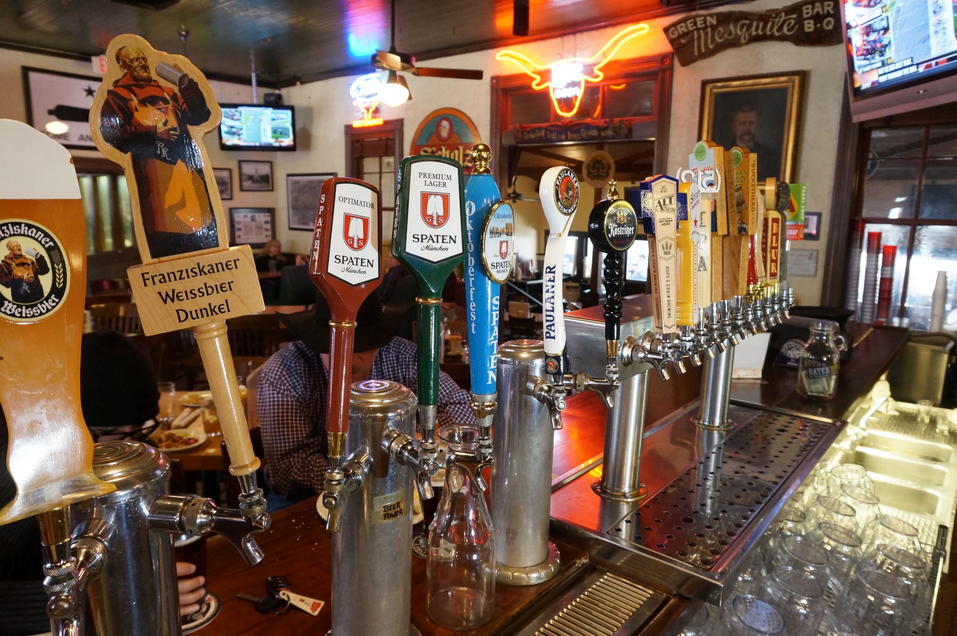 Variety of beer taps in a lively Austin, Texas bar setting.