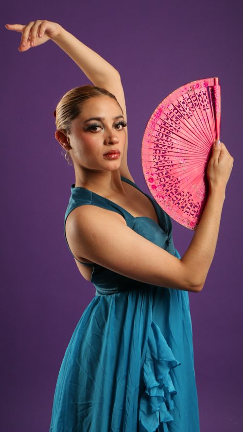 Free A poised flamenco dancer in a blue dress holds a pink fan against a purple background, exuding grace and style. Stock Photo