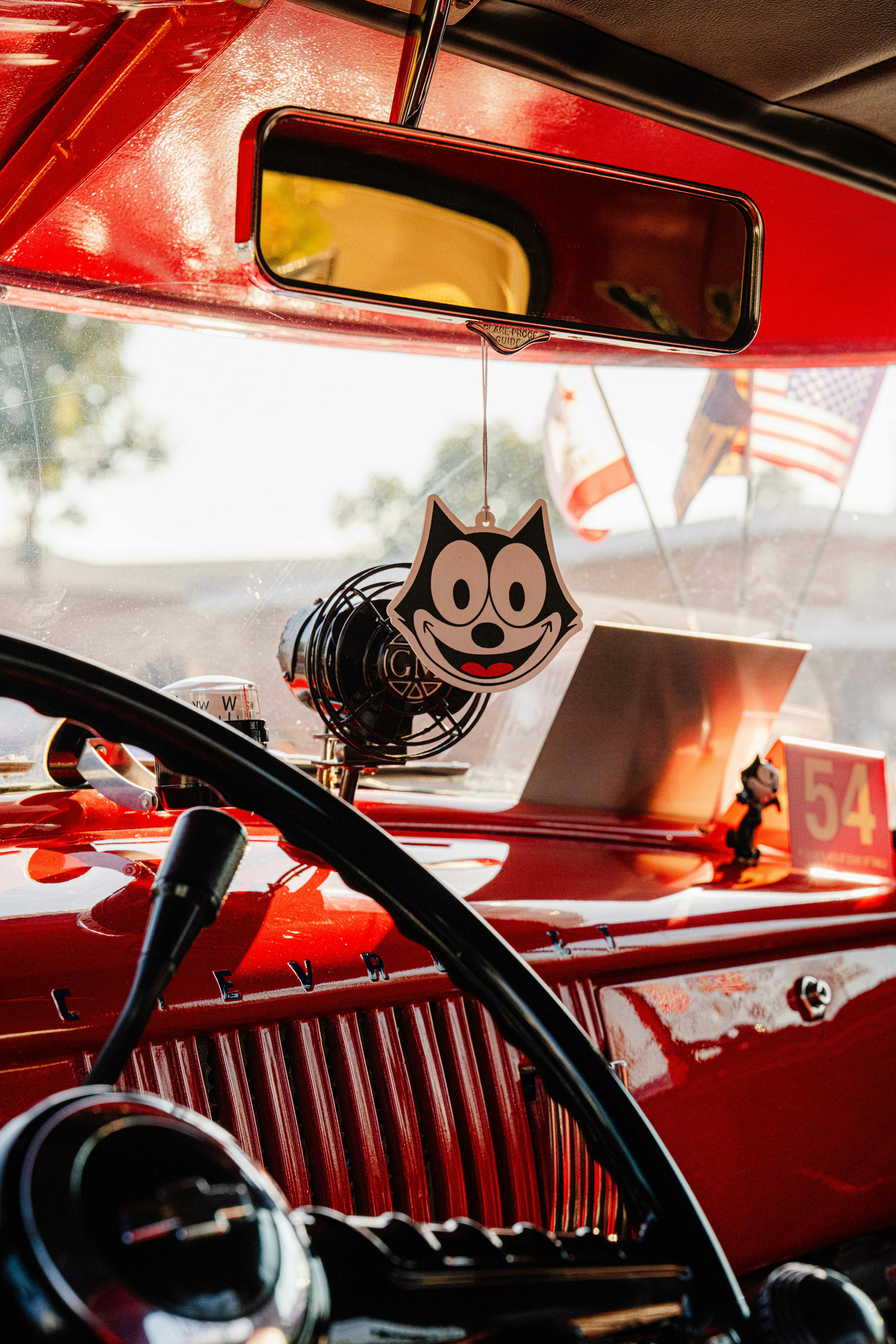 Interior view of a classic 1950s car with retro accents and a cartoon air freshener.