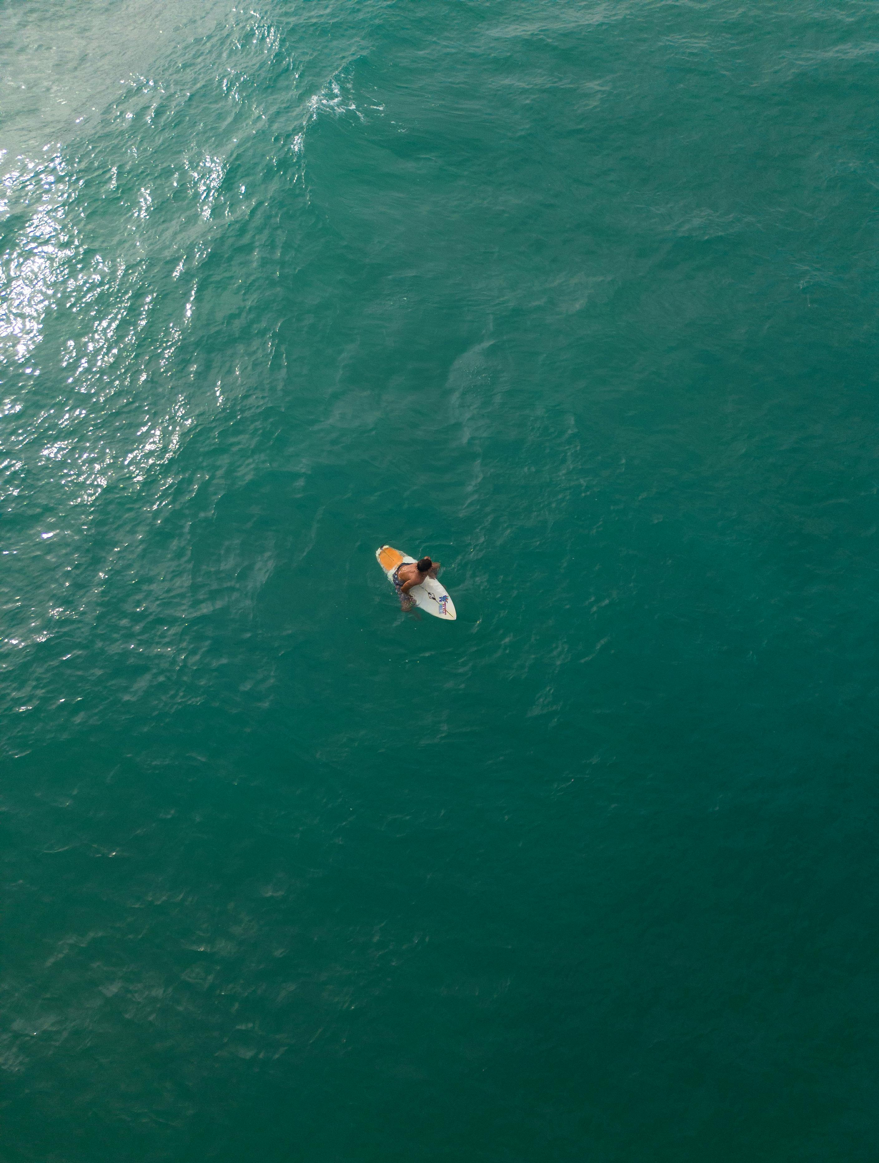 Surfer skillfully catches a wave in Brazil's vast turquoise ocean, aerial view.
