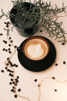 A cozy coffee cup with plant decor on a white surface, embodying café culture.