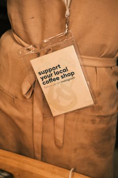 Close-up of a barista apron with a tag promoting local coffee shop support.