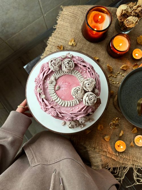Free Beautifully decorated pink cake with flowers, surrounded by candles and rustic decor. Perfect for celebrations. Stock Photo