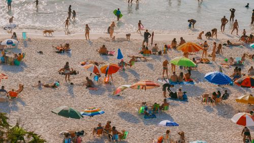 Free A crowded beach scene with colorful umbrellas and people relaxing in the sunlight. Stock Photo