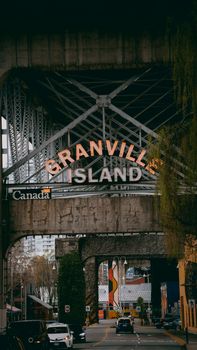 View of Granville Island sign beneath bridge structure in Vancouver, Canada.