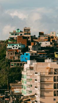 A vibrant view of diverse buildings on a hillside under a partly cloudy sky.