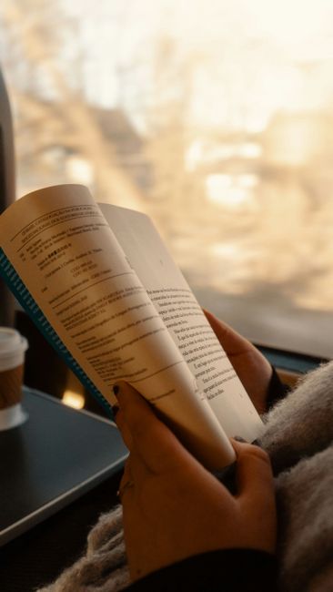 A cozy train setting with a person reading a book and a coffee cup.