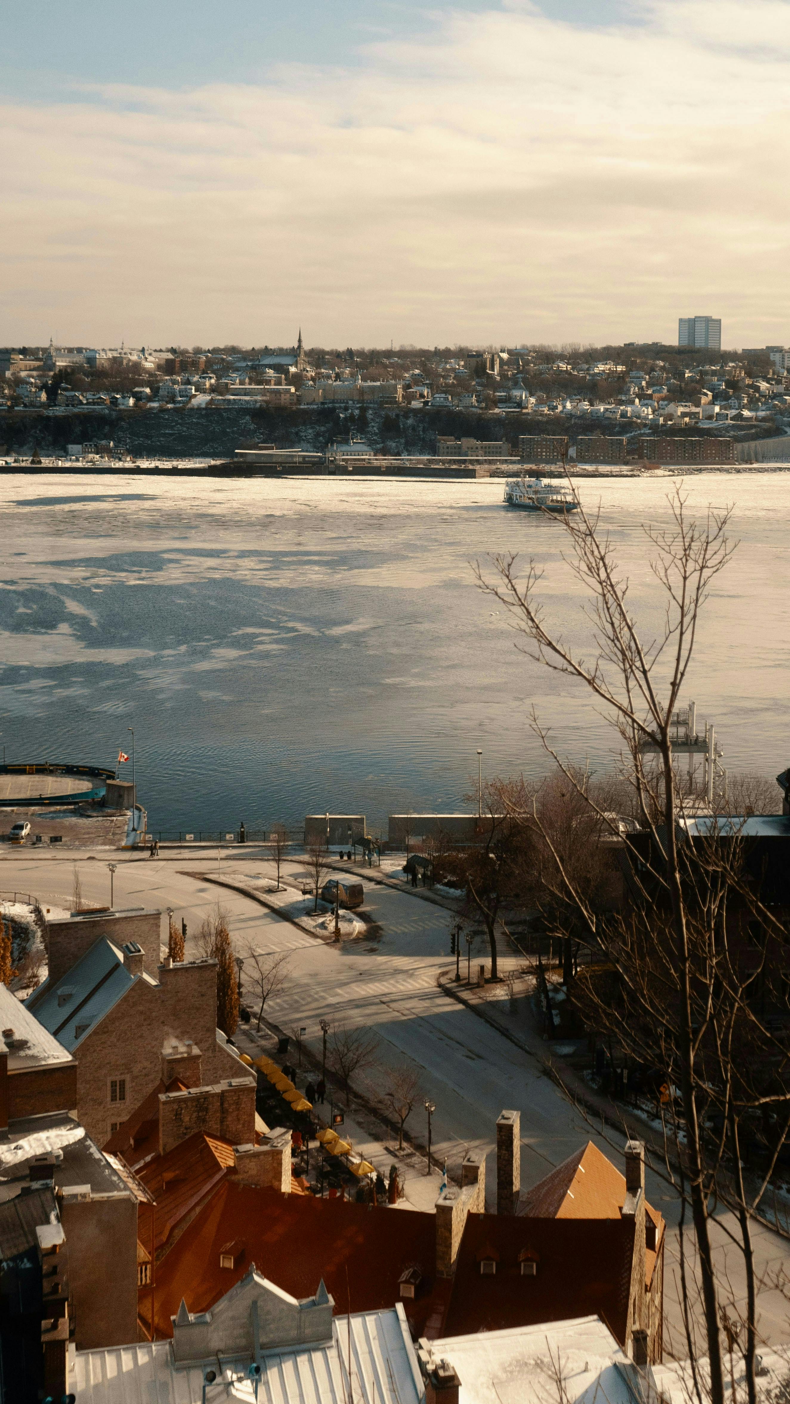A serene winter view of a river and cityscape from above, showcasing urban beauty.