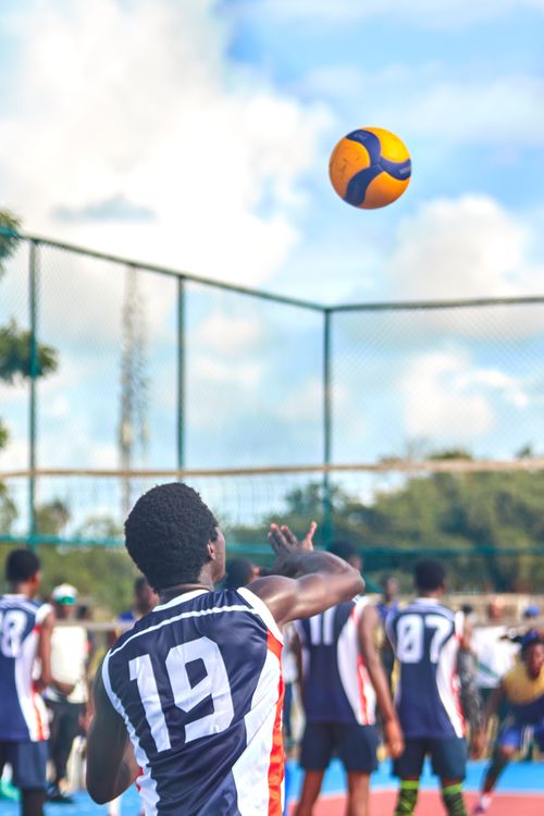 Free Athletes competing in a dynamic outdoor volleyball match on a sunny day. Stock Photo