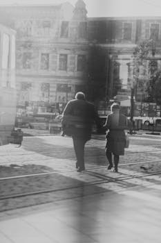 Two adults walking in Oradea, Romania, reflected on a glass surface in a vintage black and white style.