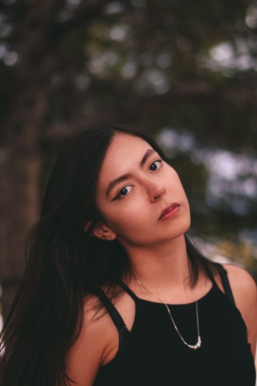 Free Captivating portrait of a young woman standing outdoors with a serene background. Stock Photo
