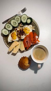 A hearty breakfast featuring eggs, smoked salmon, and a coffee cup.