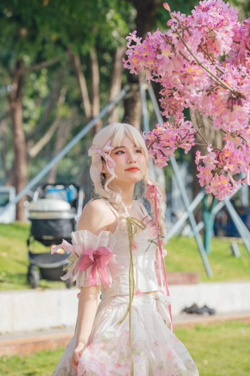 Free A cosplayer in fantasy attire poses by pink cherry blossoms outdoors. Stock Photo
