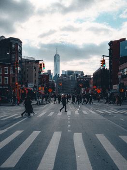 Street view of pedestrians crossing with One World Trade Center in the background.