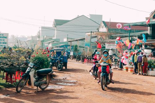 Free Vibrant Asian street market scene with motorcycles and colorful decorations during the day. Stock Photo