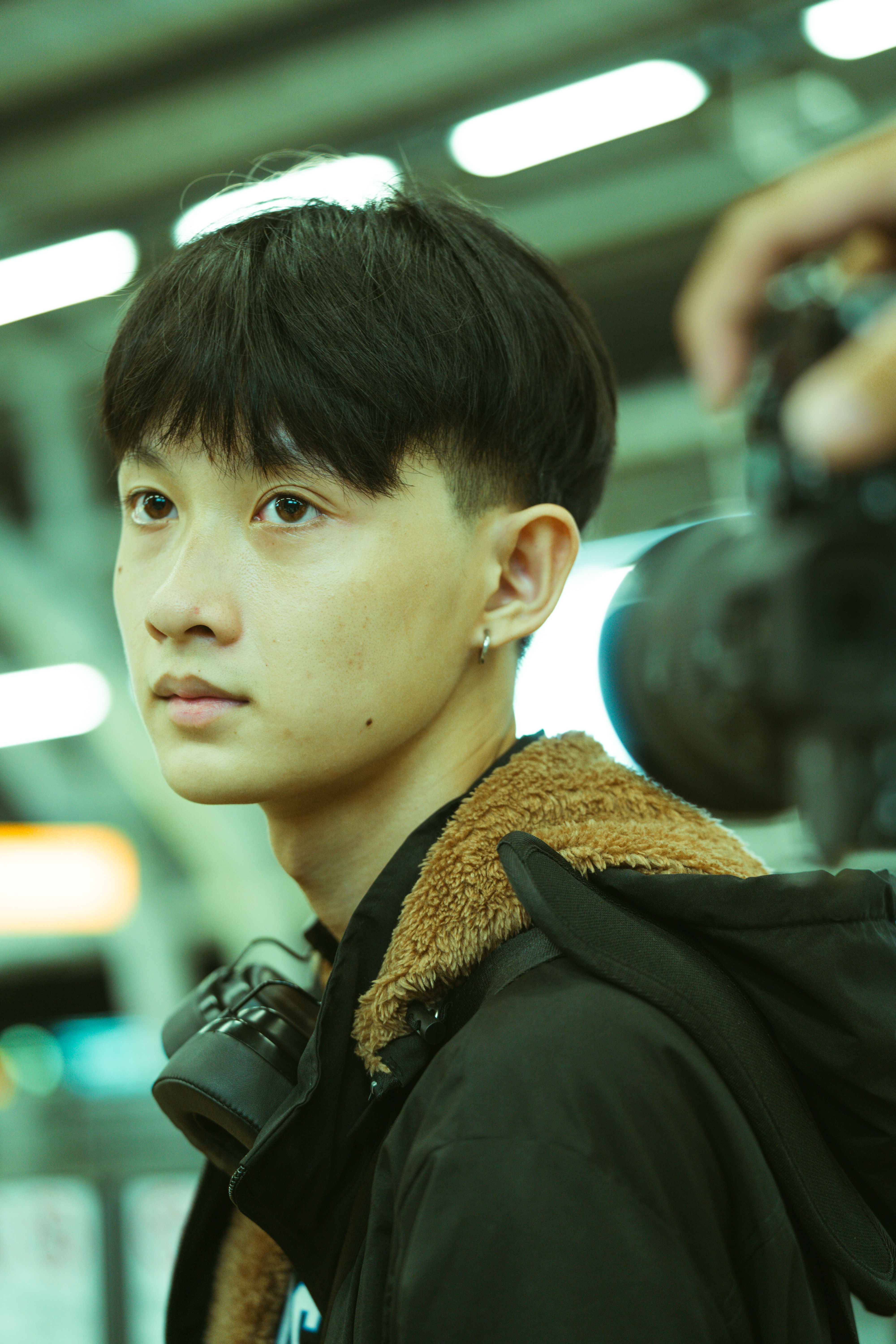 Close-up of a young man in an urban indoor setting with camera gear.