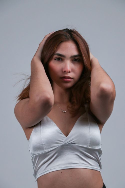 Free Portrait of a confident young woman with hands in her hair posing indoors. Stock Photo