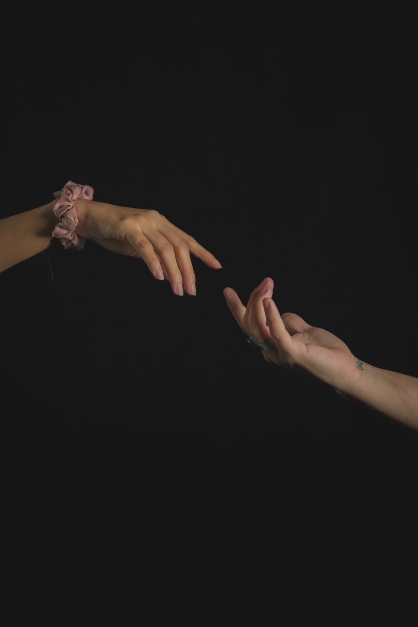 Two hands reaching toward one another in darkness — photo by Kevin Vásquez Abudeye on Pexels