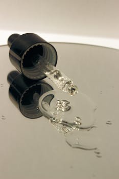 Close-up of a transparent serum dropper with liquid reflecting light.