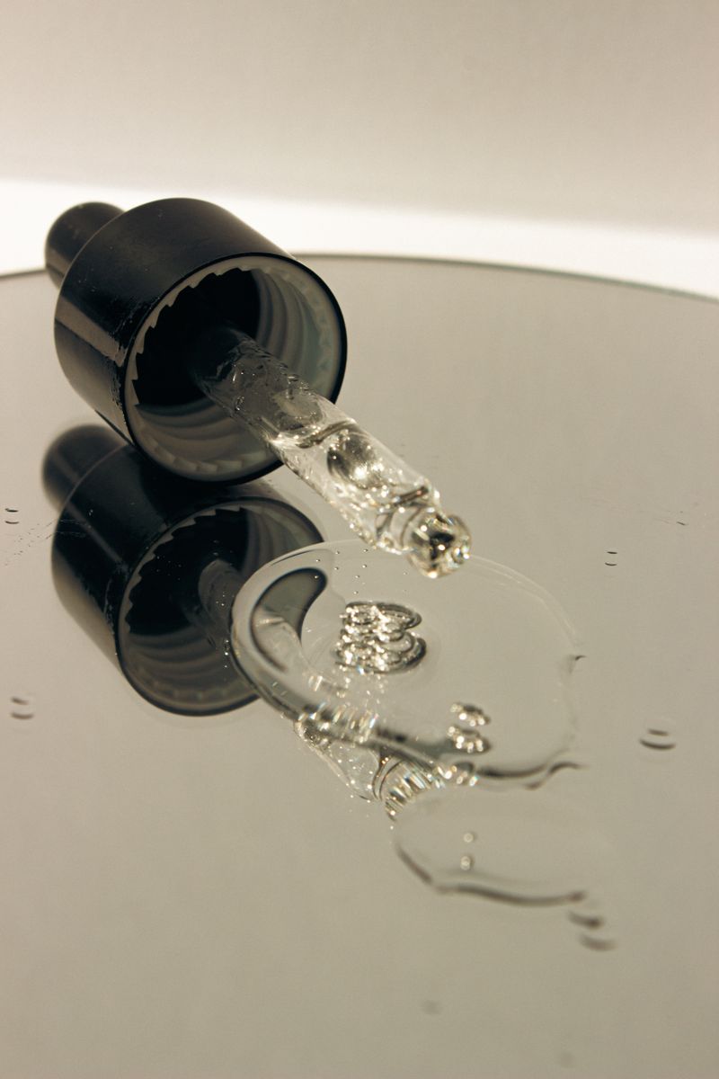 Close-up of a transparent serum dropper with light refracting through the liquid