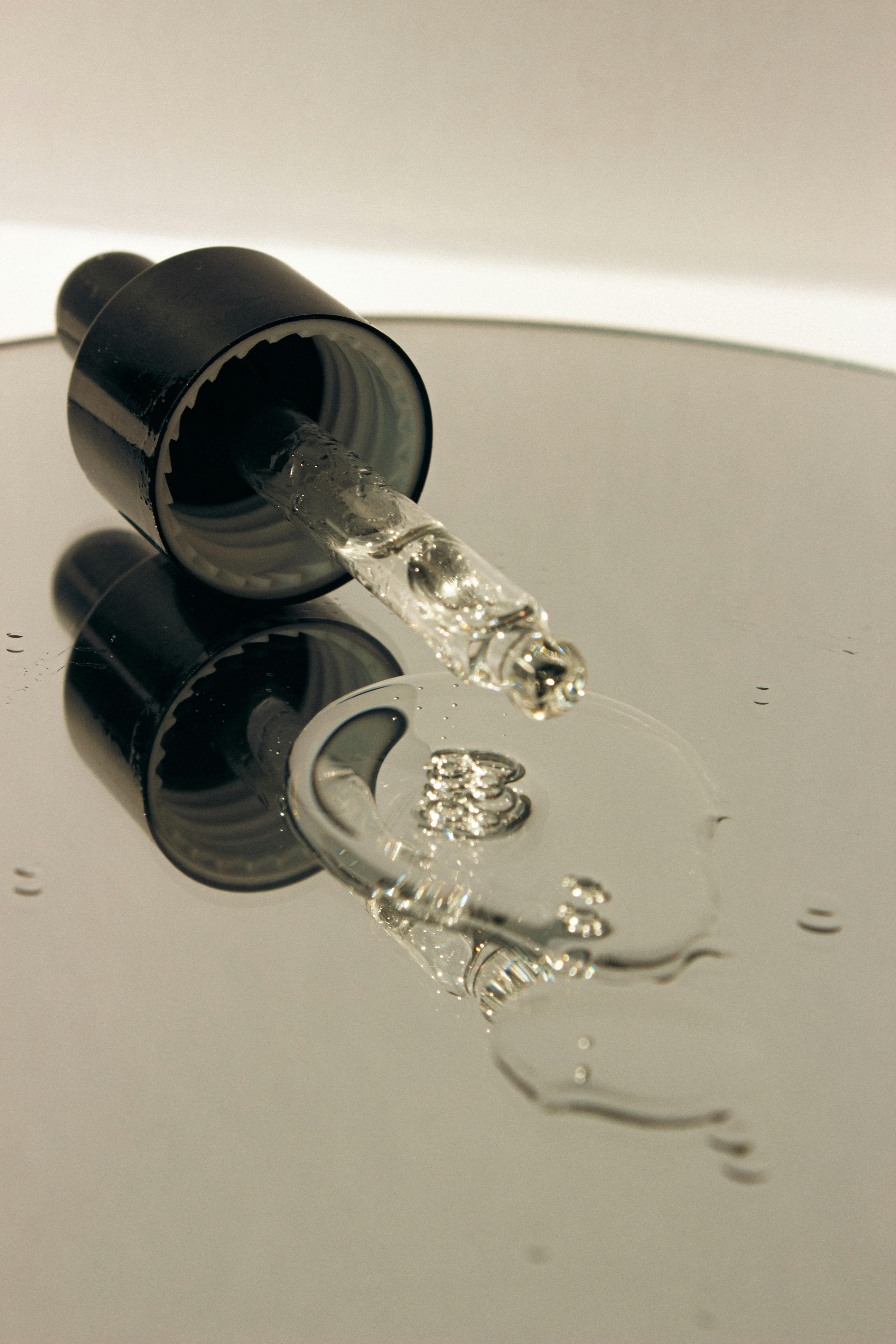 grátis Close de um conta-gotas de soro transparente com líquido refletindo luz. Foto profissional