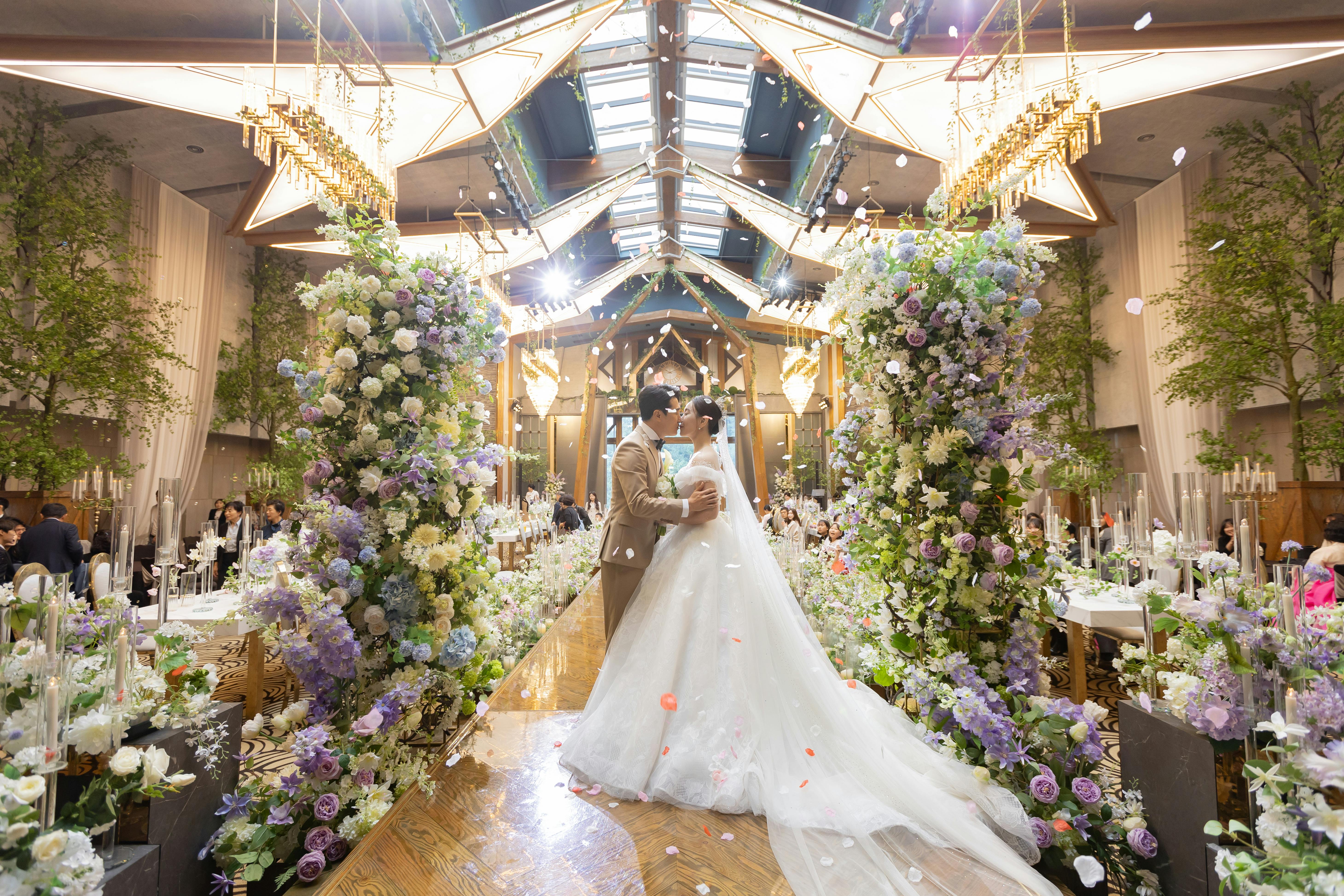 A couple dancing amidst a lavish floral wedding setup in a grand venue.