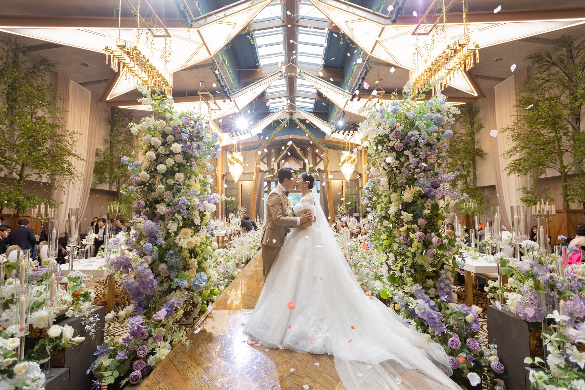 A couple dancing amidst a lavish floral wedding setup in a grand venue.