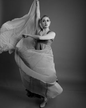 Black and white photo of a dancer in a flowing gown, capturing motion and elegance.