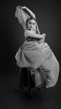 Graceful dancer poses in a flowing dress, captured in a dramatic black and white photo.