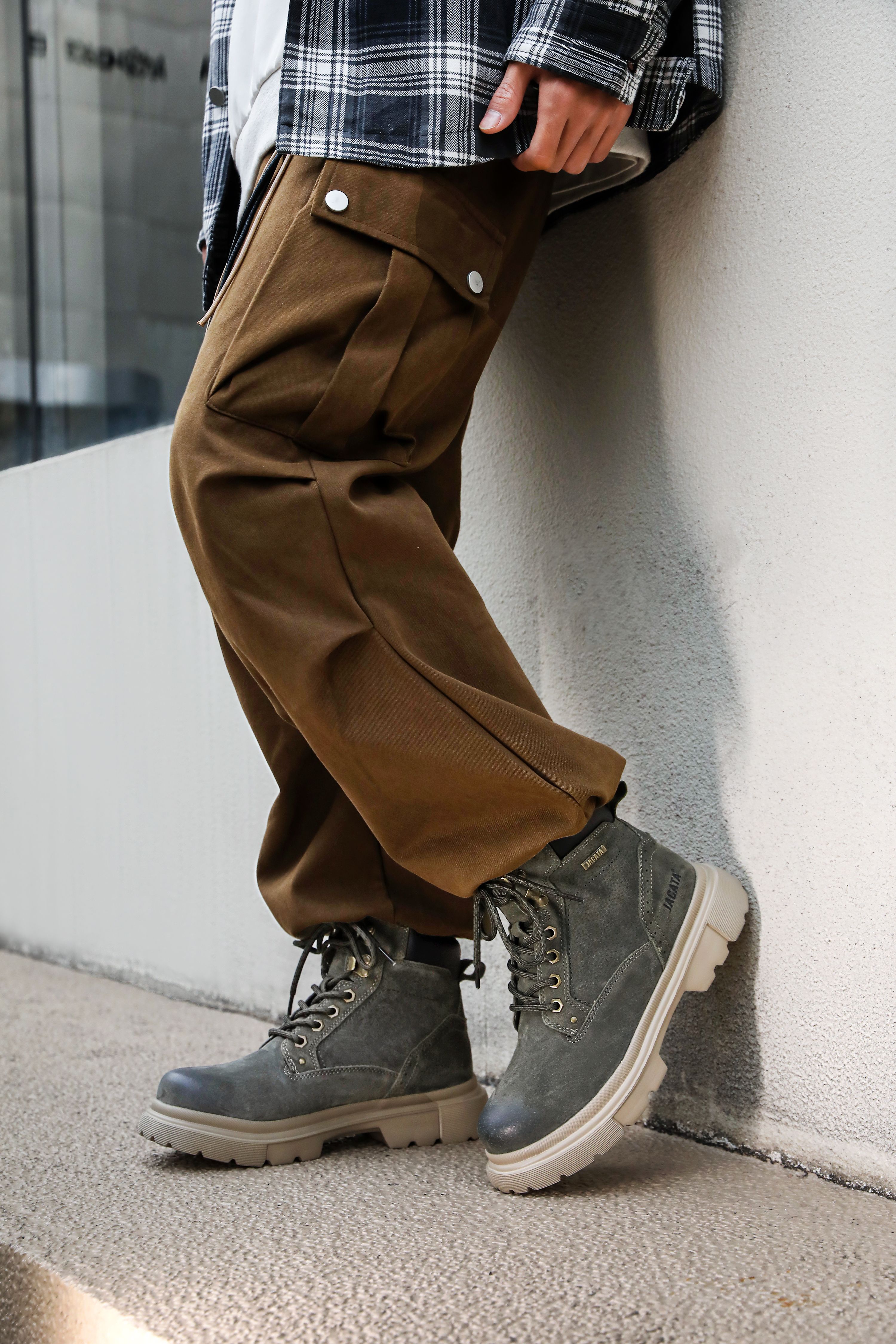 Close de um traje urbano casual com calças marrons e botas cinza.