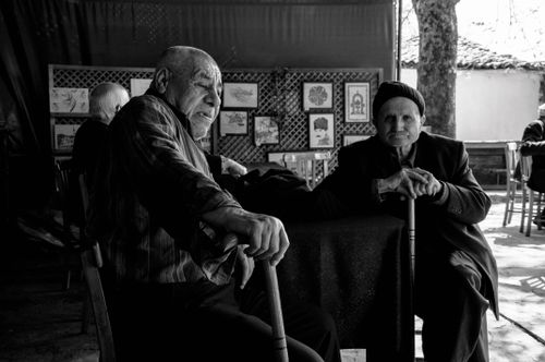Free Two senior men sitting at an outdoor café in Birgi, İzmir, Türkiye, engaged in conversation. Stock Photo