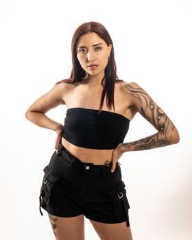 Portrait of a stylish tattooed woman showcasing confidence and elegance in a studio setting.