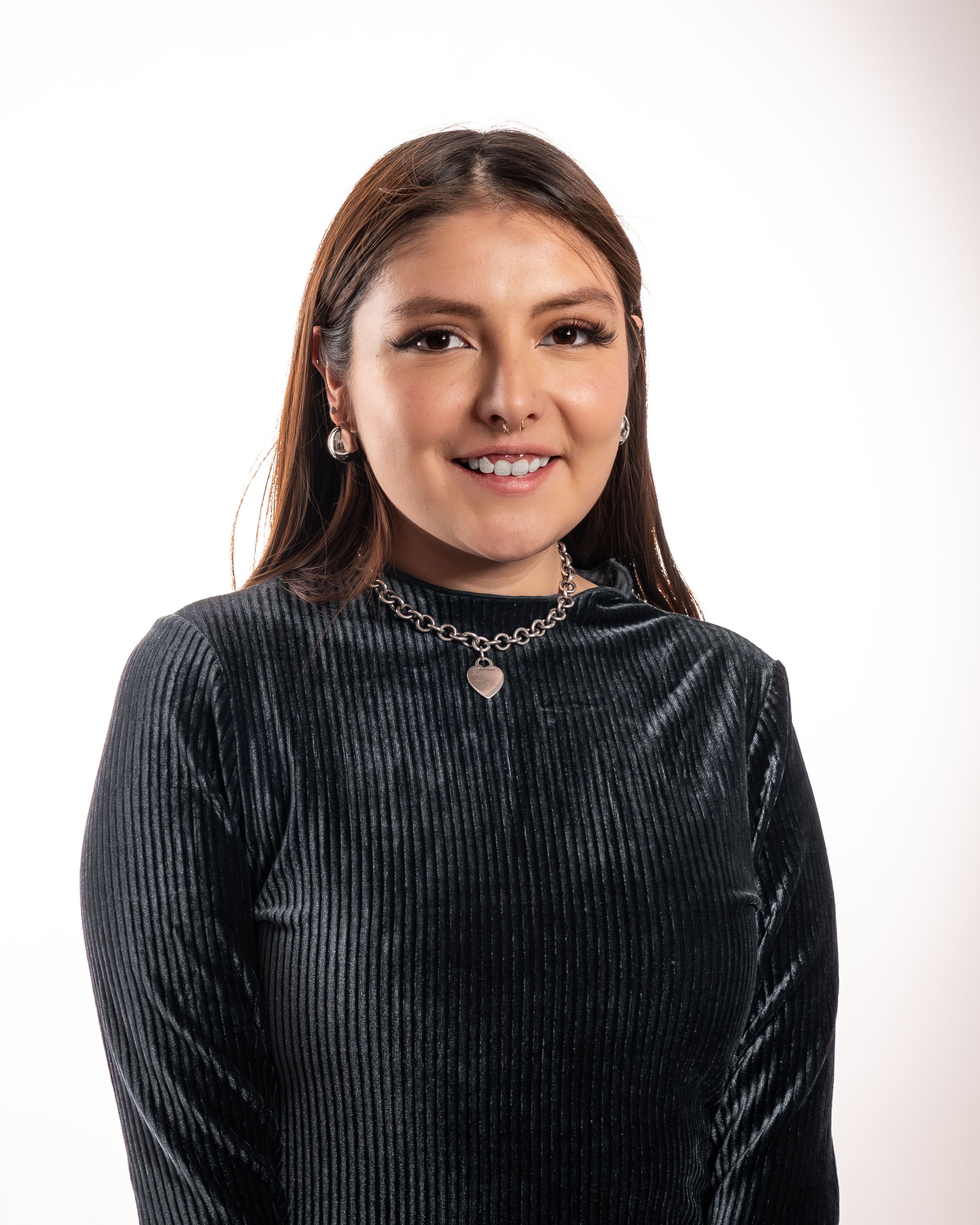 Confident Hispanic woman smiling warmly in a studio setting, exuding elegance and style.