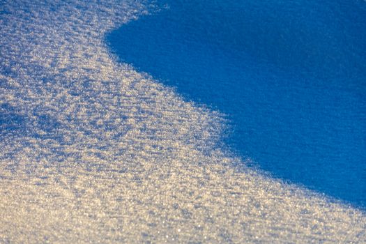 Abstract winter image showing textured snow with light and shadow play, creating a cool, serene scene.