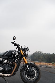 Detailed view of a black motorcycle parked on an open road in Bengaluru, India.