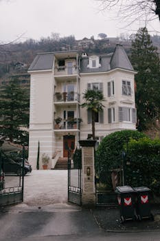 Stately multi-story building with lush surroundings, showcasing classic European architecture.