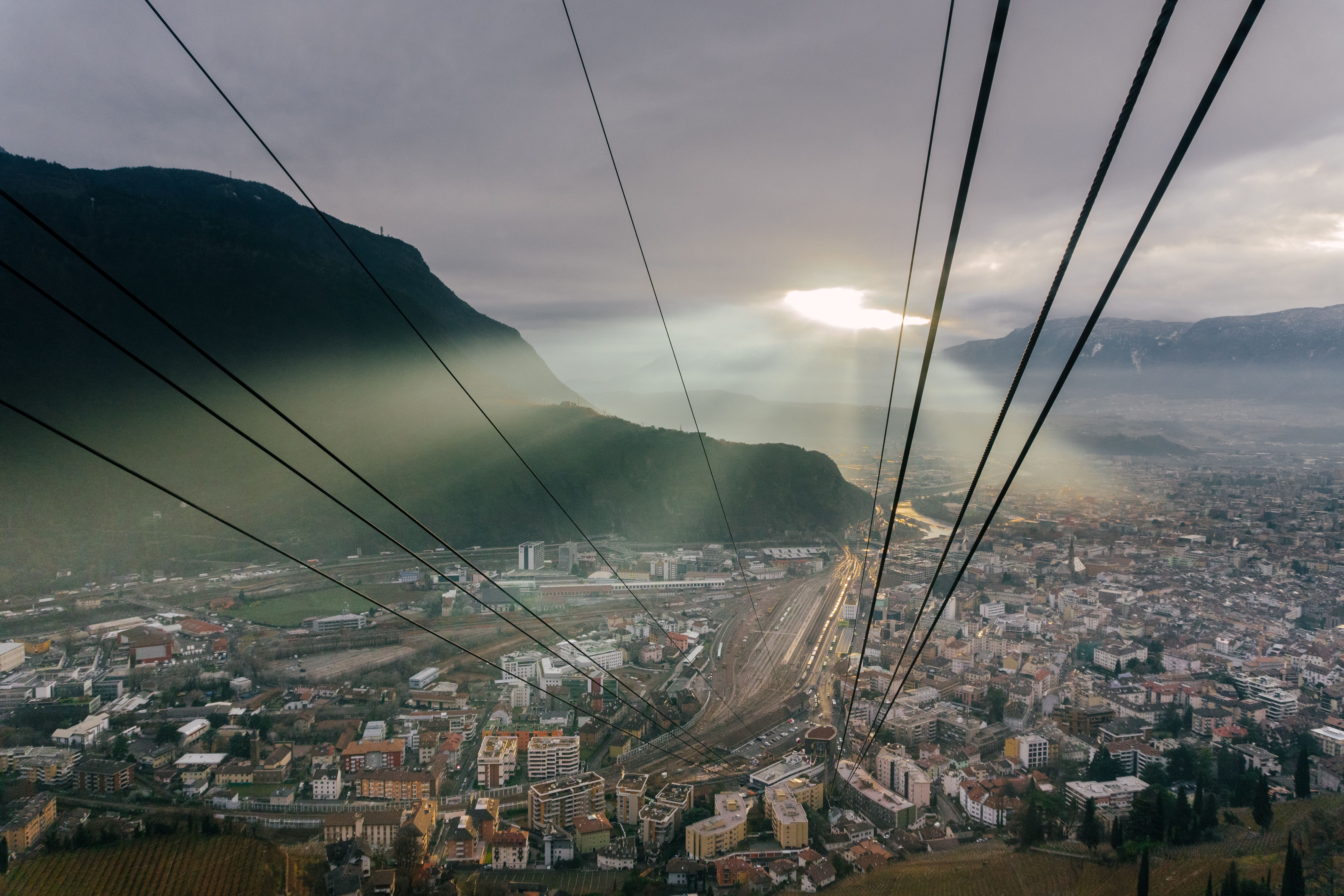 Breathtaking view of a cityscape with sunrays breaking through clouds, captured from a cable car.