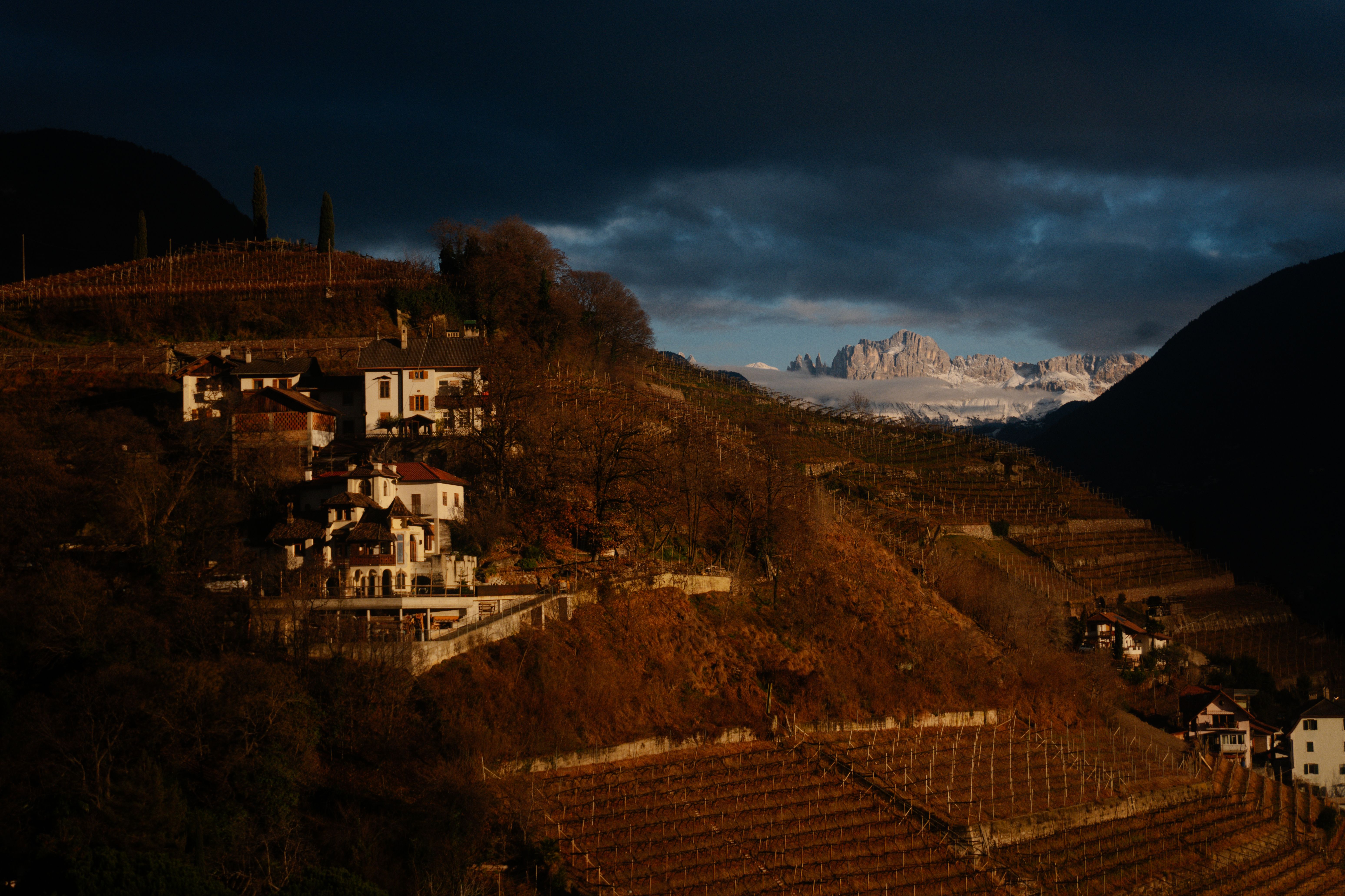 Picturesque village on a hill with dramatic mountains in twilight.