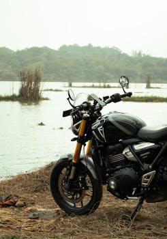 Close-up of a black motorcycle by a serene lake in Bengaluru, India, highlighting adventure and freedom.