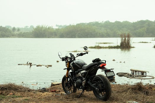 A black motorcycle parked beside a tranquil lake in Bengaluru, India, offering a sense of freedom and adventure.