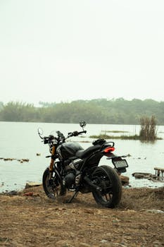 A sleek black motorcycle parked by a peaceful lakeside, perfect for bike enthusiasts.
