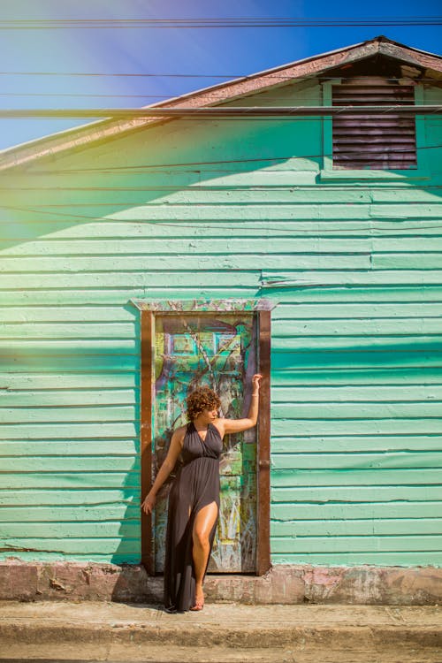 Woman in Black V-neck Sleeveless Dress Leaning on Door