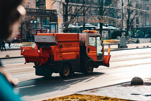 Orange street sweeper cleaning the street in Kyiv, Ukraine during daytime.