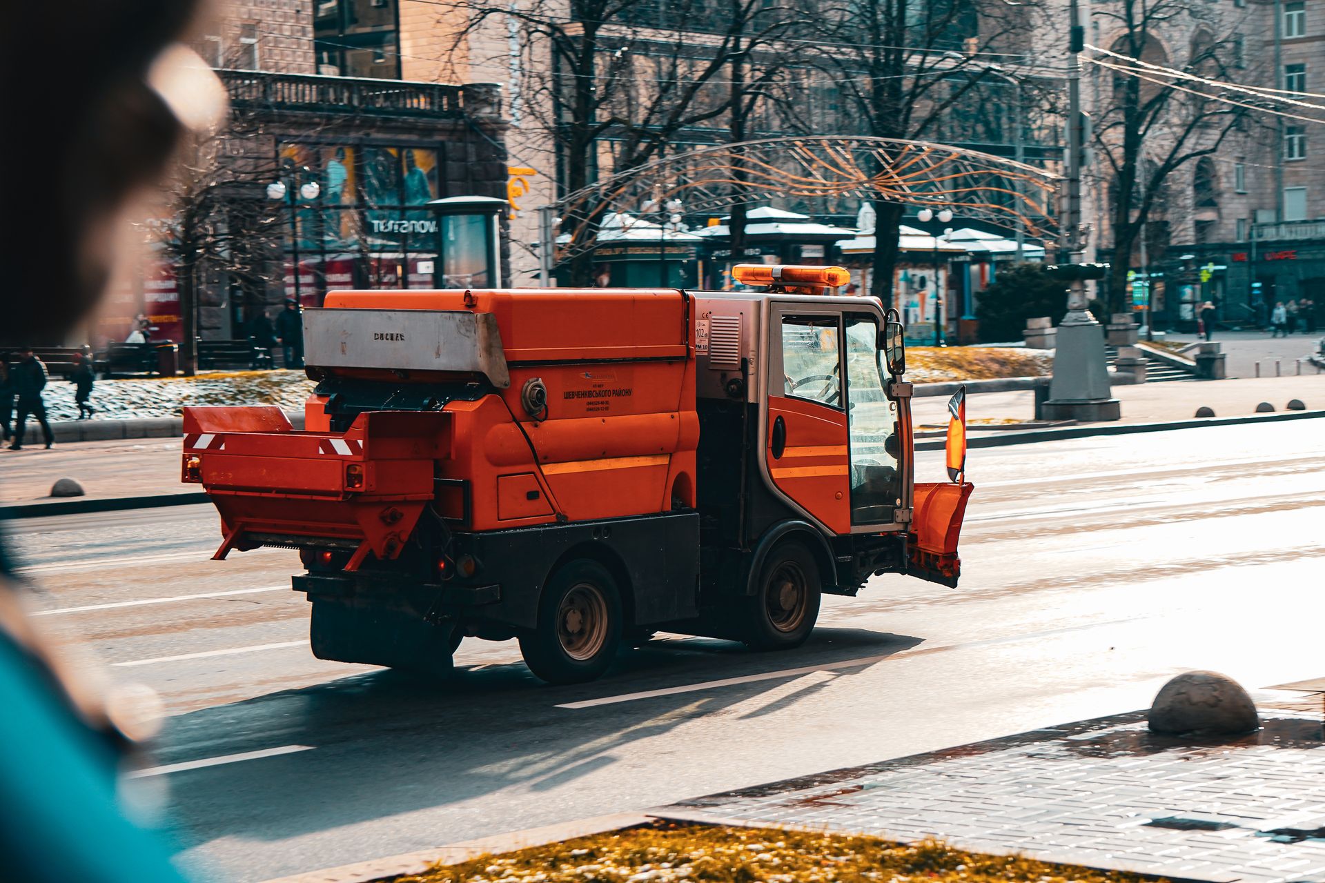 Orange street sweeper cleaning the street in Kyiv, Ukraine during daytime.