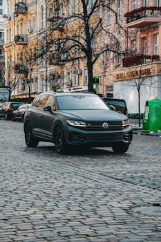 A sleek SUV on a cobblestone street in Kyiv, Ukraine, amidst historical architecture.