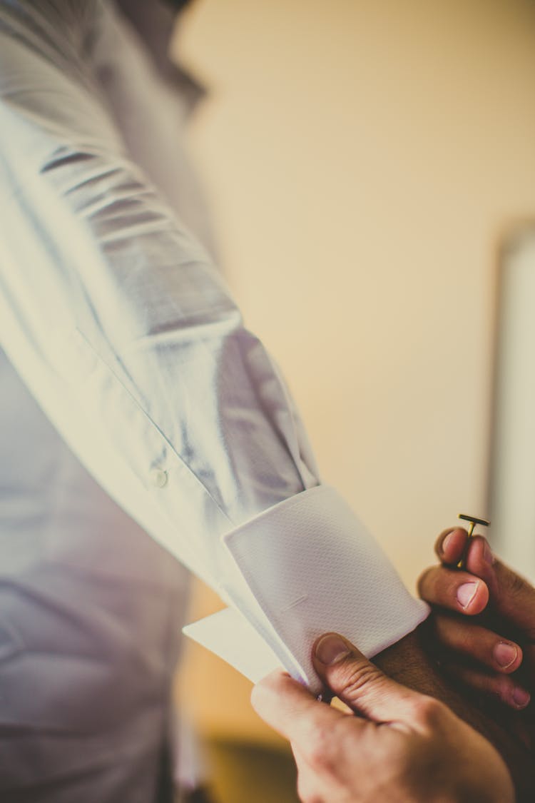 Person Putting Cufflinks On Dress Shirt