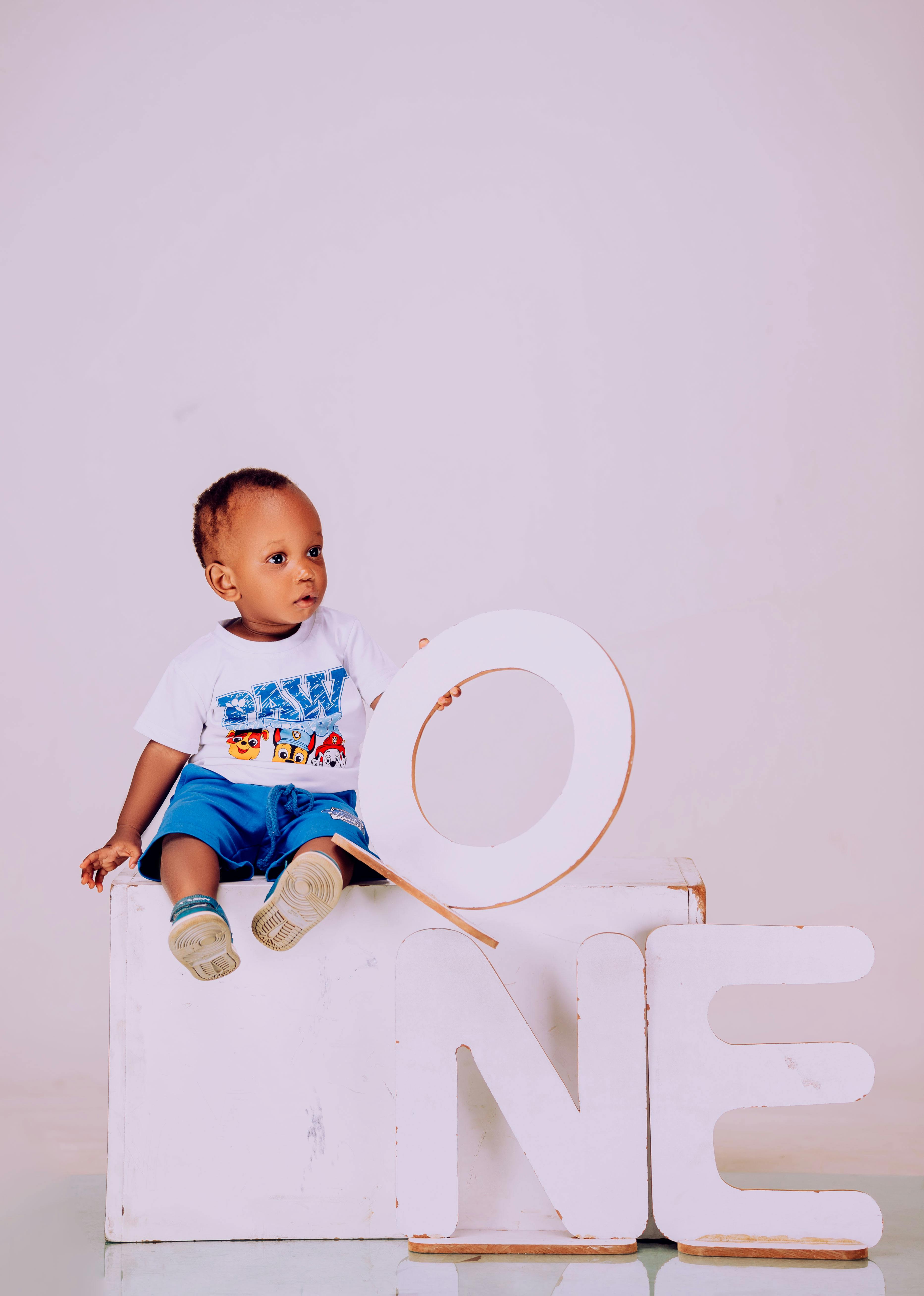 Baby celebrating first birthday with creative props in studio setting.