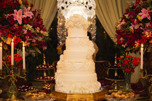 Free Luxurious five-tier wedding cake surrounded by vibrant floral arrangements and candles. Stock Photo