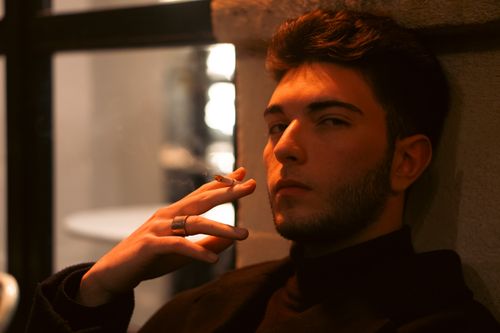 Free A contemplative young man smoking, captured in soft, warm lighting in Istanbul. Stock Photo