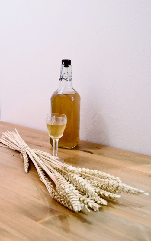 Free A bottle of wheat whiskey and barley on a wooden surface, evoking a rustic and natural feel. Stock Photo